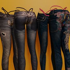 four pairs of jeans are lined up against a yellow wall, with the bottom one showing