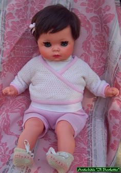 a baby doll is laying on a pink blanket