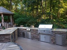 an outdoor kitchen with grill, sink and gazebo