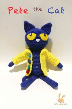 a crocheted blue cat with yellow eyes is posed in front of a white background