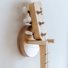 a wooden instrument hanging on the wall with strings attached to it's back end