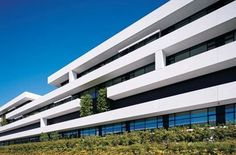 an office building with many windows and plants growing on the side of it in front of a blue sky