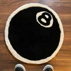 someone standing on the floor in front of a black and white rug with an eight ball logo