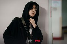 a person wearing a black hoodie leaning against a wall