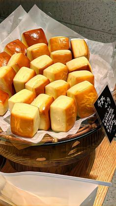 several different types of cheese on display in a glass bowl with chopsticks next to it