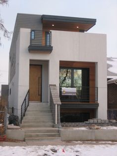 a modern home with stairs leading to the front door and second story window on one side