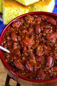 a red bowl filled with chili and cornbreads