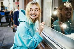 a woman standing next to a window with her reflection in the glass and smiling at the camera