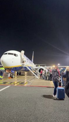 an airplane is parked on the tarmac with people standing around it and luggage being loaded