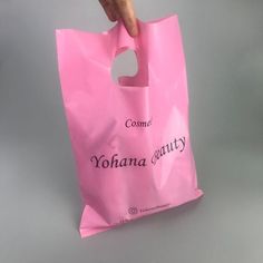 a person is holding a pink bag with the words yohana beauty on it and pointing at it