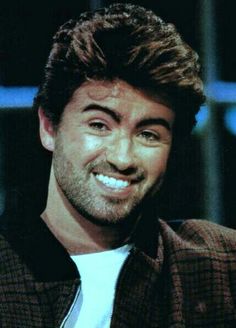 a close up of a person wearing a shirt and tie smiling at the camera with a smile on his face