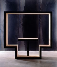 a black and white sculpture sitting on top of a wooden table in front of a metal wall