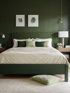 a bedroom with green walls, white bedding and two framed pictures on the wall