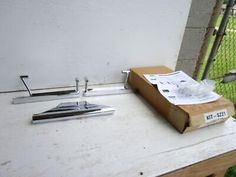 a piece of metal sitting on top of a wooden table next to a box and knife