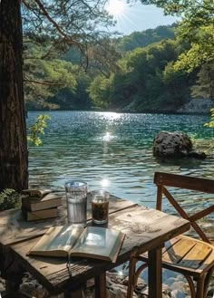 an outdoor table and chairs on the shore of a lake with trees in the background