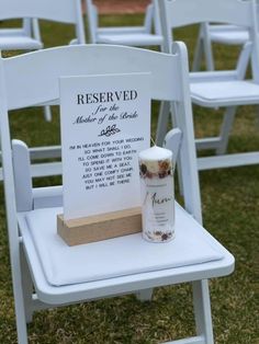 a white chair sitting on top of a grass covered field next to a wooden sign