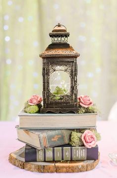 there is a small clock on top of two books and flowers in front of it