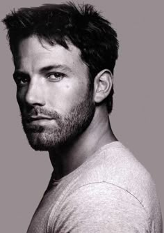 a black and white photo of a man with a beard wearing a t - shirt