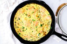 an omelet with shrimp and parsley in a cast iron skillet on a white table