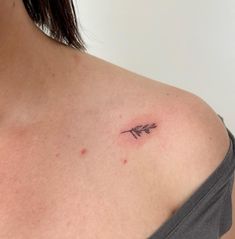 a woman's shoulder with an arrow tattoo on the left side of her chest