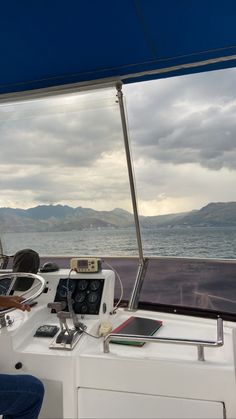 a man sitting on the back of a boat in front of an open ocean and mountains