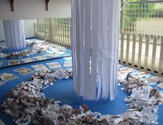 a room filled with lots of papers on top of a blue floor covered in white sheets