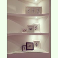 three white shelves with framed pictures on them