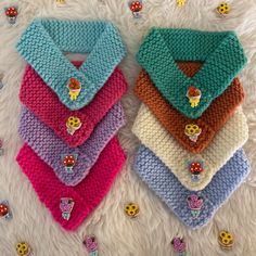 four knitted scarves with cartoon characters on them sitting on a white fur surface