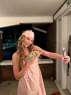 a girl in a pink dress is holding a stuffed animal and smiling at the camera