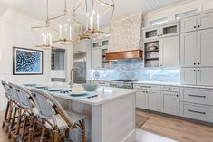 a large kitchen with white cabinets and an island in front of the stove top oven