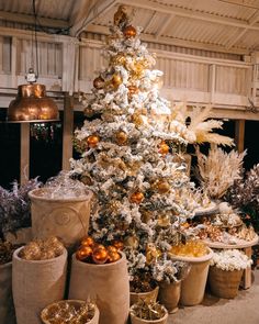 a white christmas tree with gold ornaments and other holiday decorations in baskets on the floor