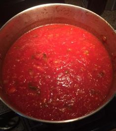 a pot filled with red sauce sitting on top of a stove