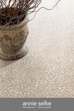 a vase filled with twigs on top of a carpet