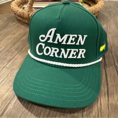 a green hat with the word amen corner on it sitting on a wooden floor