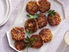 several crab cakes on a white plate next to a glass of milk and napkins