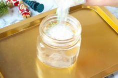 a person is pouring something into a glass jar on a tray with other christmas decorations in the background