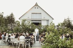 a group of people that are standing in front of a building with trees and bushes