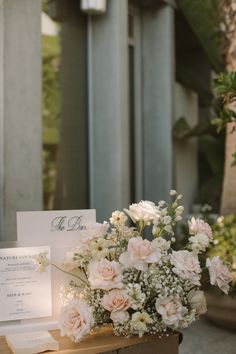 a bouquet of flowers sitting on top of a wooden table next to a white card