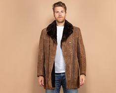 A brown vintage 70's western-style suede coat. Featuring a double-breasted button closure with two side-entry pockets, and one inside breast pocket. Made from genuine lamb suede leather and lined with a soft and warm faux shearling, the inside of the arm sleeves is lined with quilted synthetics.  Vintage condition level: 8/10. Showing some watermarks on the left-hand arm sleeve.  Model Janis is 6.16 ft (188 cm), 209.4 lbs (95 kg) and he wears the size available. SIZE: Marked size 28, fits like t Western Suede Outerwear For Winter, Western Style Suede Winter Outerwear, Brown Suede Long Coat Outerwear, Brown Single Breasted Suede Outerwear, Brown Suede Long Coat, Vintage Suede Outerwear For Winter, Mens Western Wear Coats & Jackets, Vintage Suede Long Sleeve Outerwear, Vintage Faded Pre-washed Outerwear