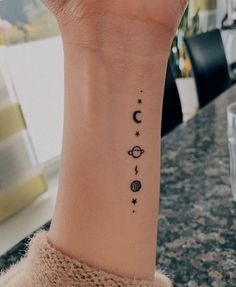 a woman's wrist tattoo with the planets and stars on her left arm,