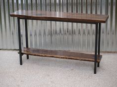 a wooden table sitting on top of a carpeted floor next to a metal wall