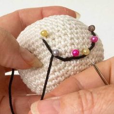 someone is crocheting a small white object with beads