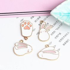 three animal charms sitting on top of a piece of paper next to a pink object