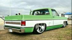 a green and white truck parked on top of a grass covered field