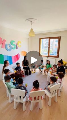 a group of children sitting around a table in a room with colorful letters on the wall