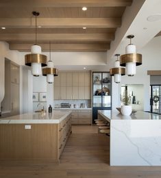 a large kitchen with wooden floors and white counter tops, along with two pendant lights hanging from the ceiling