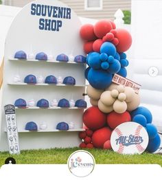 there is a display with balloons and baseballs on it in the grass near a sign that says souvenir shop