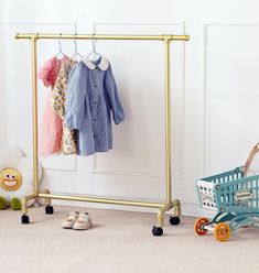 a child's clothing rack with clothes hanging on it and a shopping cart next to it