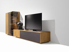 a flat screen tv sitting on top of a wooden entertainment center next to a vase