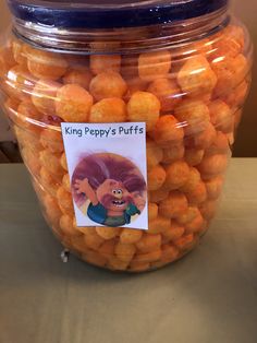 a glass jar filled with oranges sitting on top of a table next to a sign that says king peppy's puffs